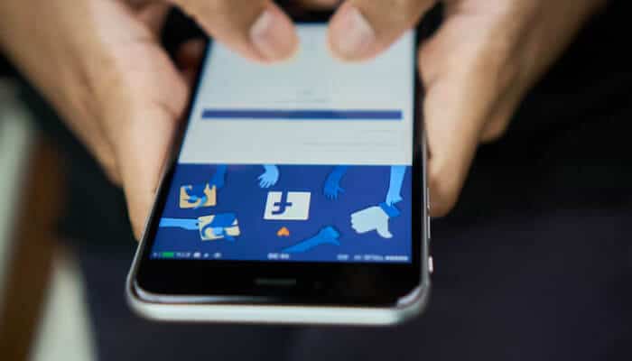 Person holding a smartphone with the Facebook login screen open preparing to log in or delete a Facebook account