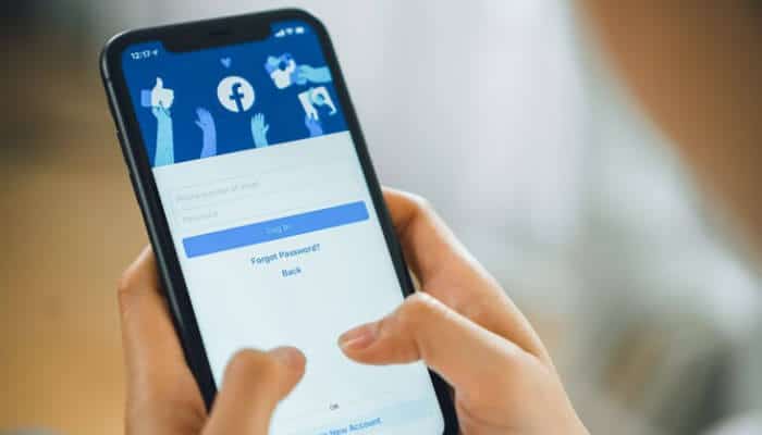 Person using smartphone to delete Facebook account, with Facebook login screen visible on the device