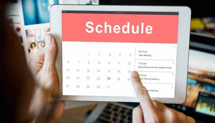 A person holding a tablet displaying a digital calendar with Schedule in bold. The image represents Social Media Marketing and digital planning.