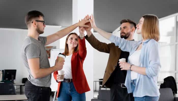 Starting a Business with young entrepreneurs in a modern office celebrating success with a group high-five showcasing teamwork and collaboration