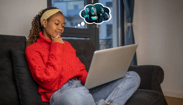 A young woman sitting on a couch using a laptop, thoughtfully trying to find a movie by describing it, with a thought bubble showing a scene from a movie