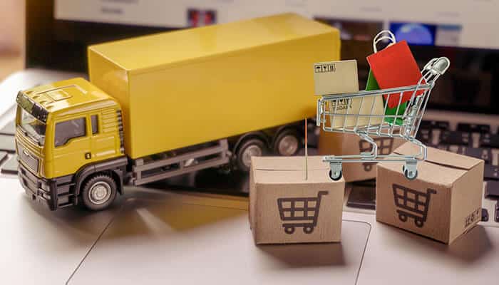 Mini shopping cart, parcels, and a delivery truck on a laptop symbolizing logistics and growth with an international ecommerce platform.