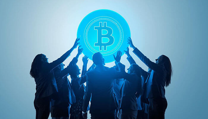 Business people reaching for a glowing Bitcoin symbol, representing growth, innovation, and investment opportunities in the top 100 cryptocurrencies.