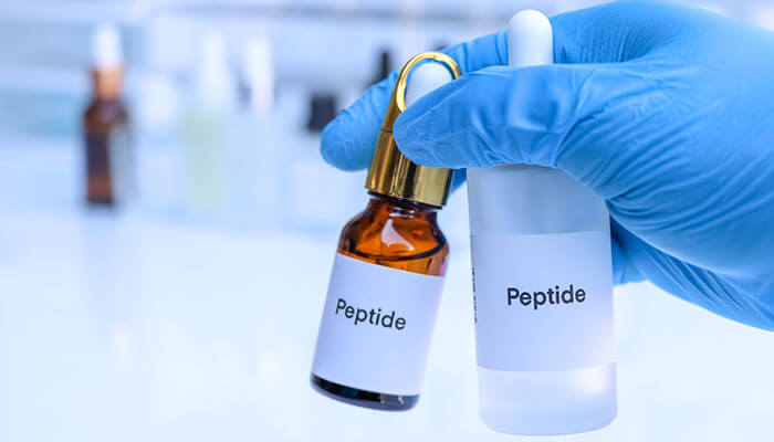 Decoding the Complexities of Peptide Synthesis - Startupeditor | Startup Editor Scientist holding peptide bottles in a laboratory, showcasing research peptides used in scientific studies and therapeutic applications