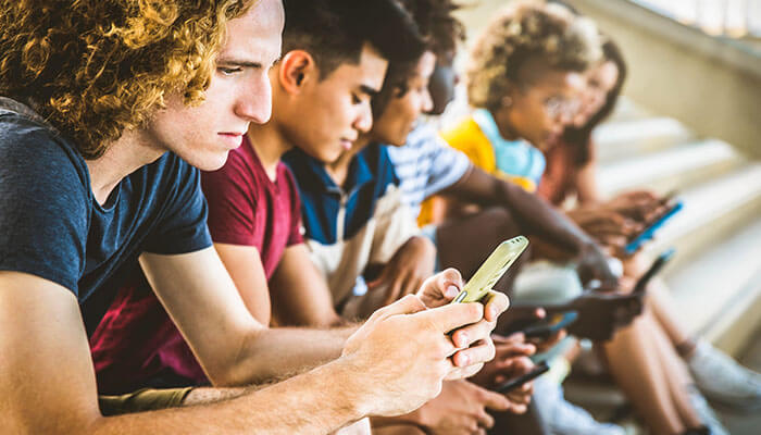 Mobile Performance Determines Success - Startupeditor | Startup Editor Group of young people using smartphones, highlighting the importance of mobile performance when you create a business website.