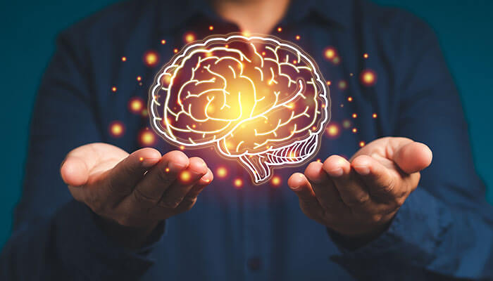Person holding a glowing brain illustration, symbolizing the impact of neuroscience in digital learning on focus, memory, and engagement
