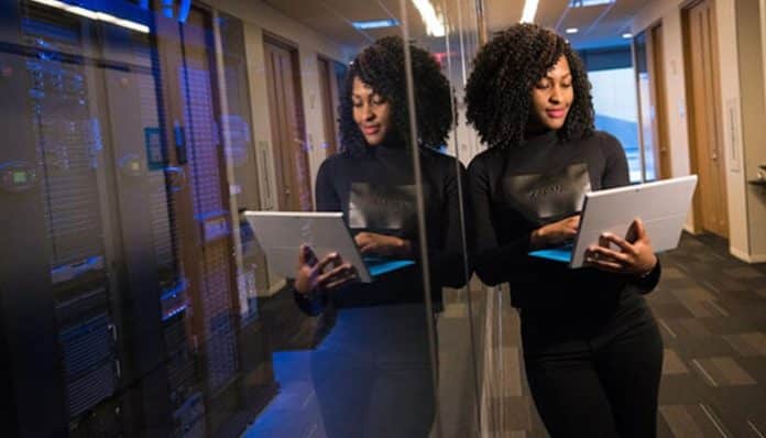 Professional woman using an Opportunity Management Tool on a tablet in a modern office setting, reflecting on her work and data analysis.