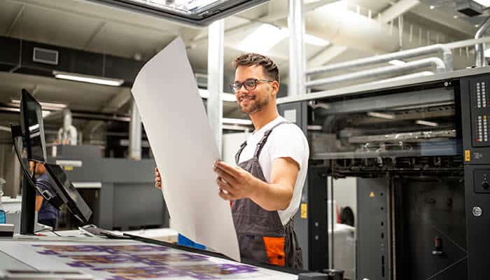 Professional Printing Services technician reviewing high-quality print materials to help businesses build brands with consistent design