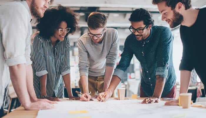 Team collaborating on business roadmaps, brainstorming strategies and planning future goals together around a table