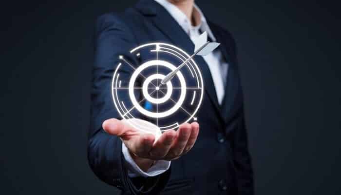 A businessperson in a suit holding a glowing digital dartboard target, representing goal setting, precision, and strategic planning essential for Business Survival.