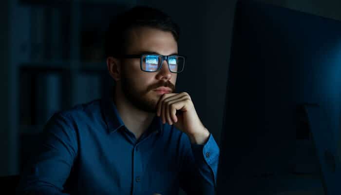 A man wearing blue light glasses while working at a computer, showcasing the comfort and protection available through Black Friday glasses deals.