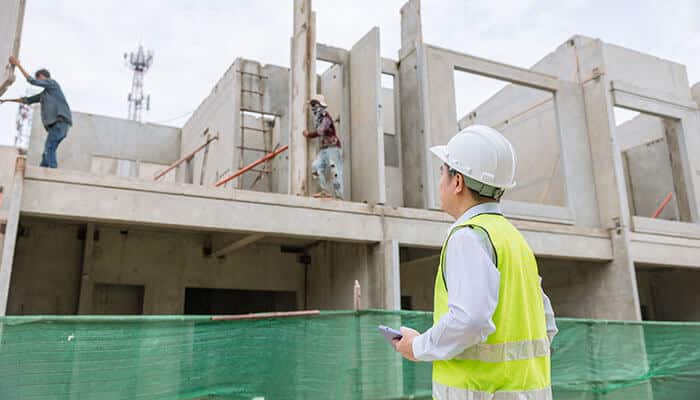 Engineer inspecting a construction site with precast concrete structures while assessing planning for precast concrete pits installation