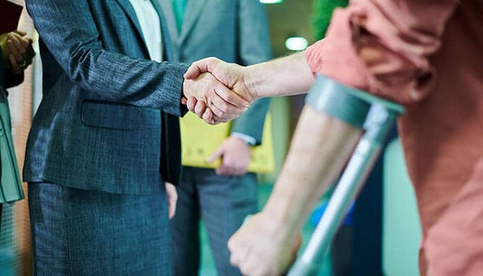 Injured client on crutches shaking hands with an attorney from Heil Law Firm